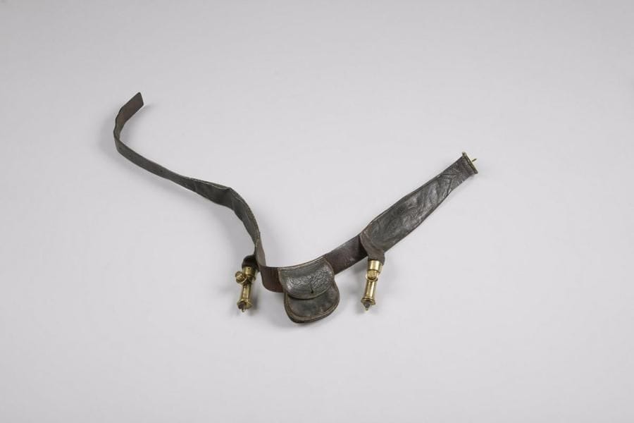 Ceinture cartouchière à poudre et à plomb, en cuir. 
Boucle et becs en laiton. 
On y joint une suspente porte-sabre et une dragonne de cavalerie en cuir brun. 