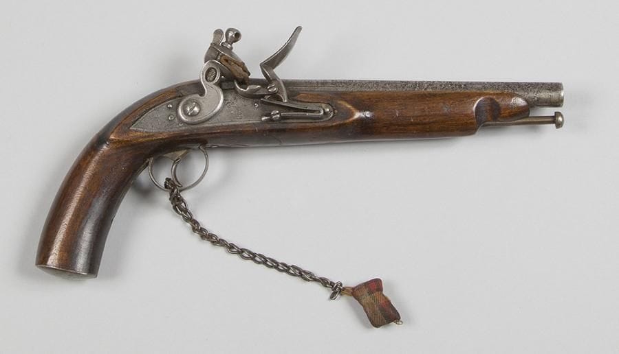 Pistolet à silex anglais. 
Canon rond à pans au tonnerre gravé de feuillages. Platine gravée d’un lion, datée « 1801 » et chien à corps plat. Garnitures et baguette en fer. Crosse en noyer. 
Avec une chaînette terminant par un coussinet. 
A.B.E. 