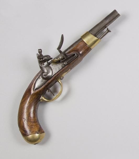 Pistolet d’arçon à silex modèle AN XIII. 
Canon rond à pans au tonnerre, poinçonné et daté 1807. Queue de culasse avec restes de marquages « M An 13 ». 
Platine marquée « Maubeuge Manufre Imple ». Garnitures en laiton poinçonnées. Crosse en noyer avec cachet. Baguette en fer. 
A.B.E. (accident à la vis de noix). 