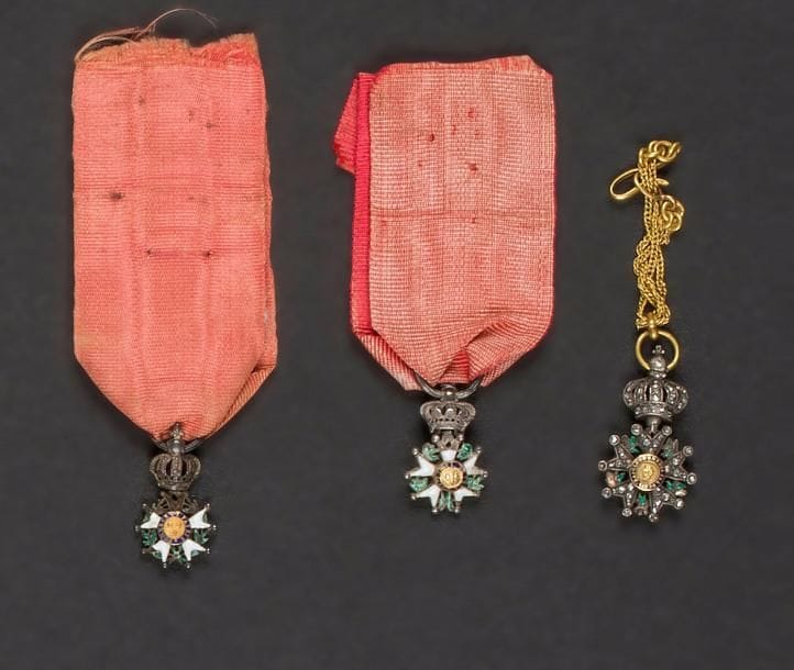 FRANCE
ORDRE DE LA LÉGION D’HONNEUR, institué en 1802.
Trois miniatures :
- étoile de chevalier de 4e type, modifié sous la restauration (manque un centre). Poinçon au faisceau de licteur. Ruban.
- étoile de chevalier d’époque restauration (manques à l’émail).
- étoile de chevalier d’époque second empire, avers garni de brillants. Avec une chaînette en or.
Poids brut total : 6 g 
T.T.B.