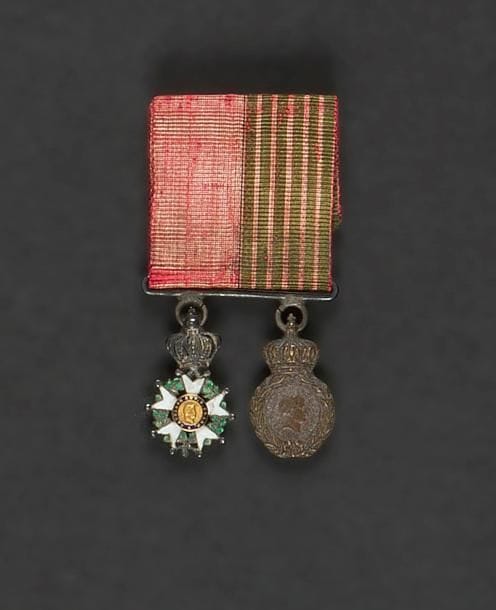 FRANCE
ORDRE DE LA LÉGION D’HONNEUR, institué en 1802.
Barrette en argent de deux miniatures :
- étoile de chevalier de la Légion d’honneur d’époque Second Empire.
Argent, or et émail.
- Médaille de Sainte-Hélène. Bronze patiné.
Ruban tissé aux couleurs des deux médailles.
Hauteur : 2,2 cm- Poids brut :18 g
T.T.B.


Provenance : vente des collections du Palais Princier de Monaco.