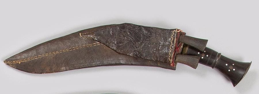 Couteau népalais Koukriss.
Monture en cuivre, poignée en corne. Lame à dos plat. Fourreau en bois recouvert de cuir avec deux batardeaux.
B.E. XXe siècle. 