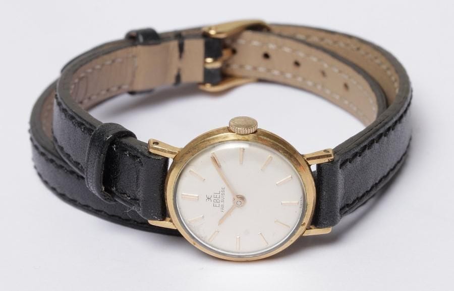 EBEL. Montre de dame en métal, cadran rond, fond satiné, index bâtons, mouvement mécanique, bracelet en cuir double tour, boucle ardillon.