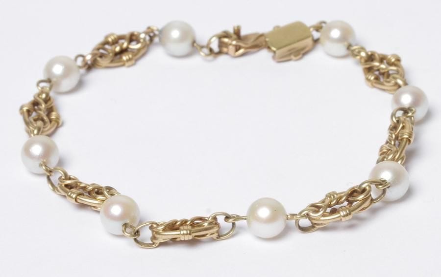 Bracelet en maillons d'or 18K (750‰) enchevêtrés scandés de 8 perles de culture. Longueur : 20 cm environ. Poids brut : 11,4 g