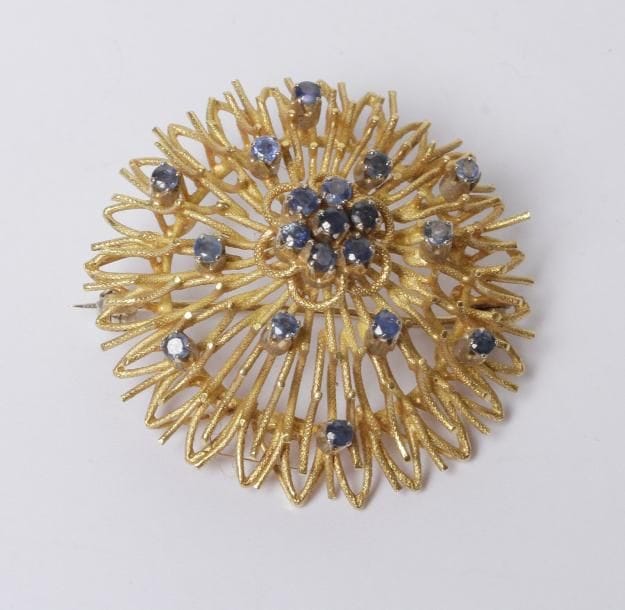 Broche en fils d'or jaune 18K (750‰) formant un pompon stylisé, piquée de saphirs. Poids brut : 15,3 g (égrisures)