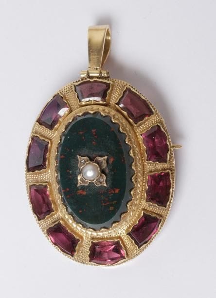 Broche-pendentif en or 18K (750‰), orné d'un jaspe sanguin dans un entourage de grenats. Travail du XIXe siècle. Hauteur : 3,5 cm environ. Poids brut : 11 g