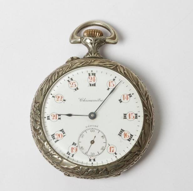 Montre gousset années 30 en métal. Chiffres arabes pour les heures, romains pour les minutes. Cadran émaillé (fêle), trotteuse à 6H, échappement à ancre. Le fond en argentan à décor repoussé d'une allégorie de la paix et portant l'inscription "Pro pace".
