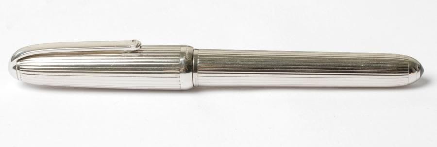 CARTIER
Stylo à plume en métal argenté le corps et le capuchon godronnés
Plume en or blanc 18K (750‰) 
Capuchon à vis
Poids brut : 56 g