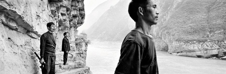Zeng Nian (né en 1954)
Zeng Nian, fils d'un professeur des Beaux Arts et d'une mère pharmacienne, livré à luimême dès le plus jeune âge dans une Chine en pleine explosion de la Révolution Culturelle, découvre la photographie dans la rue par des moyens souvent rudimentaires. Flirtant avec la délinquance, travaillant ensuite comme docker au port de Nanjing, Zeng Nian réalise ses premiers reportages. Dès le début des années 1980, s'inscrivant dans la tradition des mendiants vagabonds, il entreprend de longs voyages vers l'Ouest chinois. Marié en 1984 à une française, Zeng Nian développe ses contacts avec l'Occident et se rend en France où il commence à publier ses reportages. De Sipa à Gamma en passant par l'agence Contact Presse, ses images ont depuis été publiées dans les principaux journaux et magazines étrangers. Ses reportages les plus importants, dont la construction du Barrage des Trois Gorges, lui valent l'attribution de plusieurs prix, notamment le prestigieux World Press Photo dans la catégorie Arts Stories. Désormais indépendant, Zeng Nian s'inscrit dans la lignée des grands photographes de reportage. Son style puissant et incisif fait de grands angles et de panoramiques nous plonge au coeur des réalités socio-culturelles d'une Chine en pleine mutation. Livre en préparation : Zeng Nian, Chine. Les Trois Gorges. Le plus grand barrage du monde, Editions Lieux Dits, Lyon, 2010. Le chantier du barrage des Trois Gorges du Fleuve Yangtse, mars 1997. Trois bûcherons sur l'ancienne piste creusée dans le rocher surplombant la porte de Kui (kuimen), Fengjie Chongqing 1996. Epreuve jet d'encre, titrée, signée, datée et numérotée 3/15 dans la marge inférieure, titrée et signée à la mine de plomb au verso. 61 x 135 cm avec les marges.
