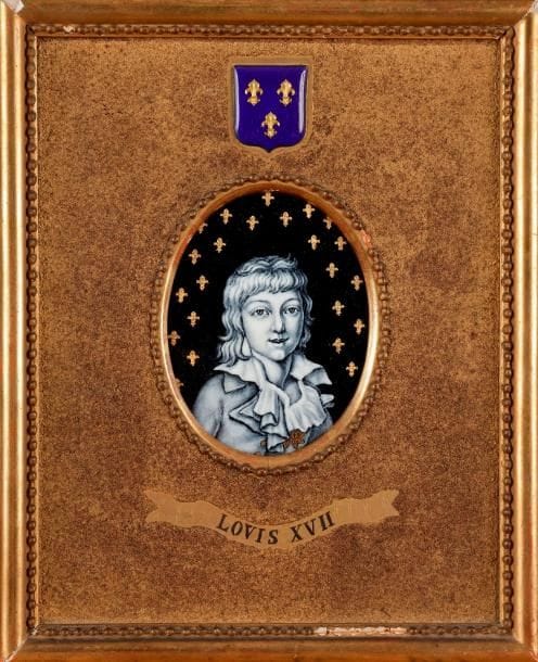 Le Dauphin Louis XVII
émail sur cuivre peint en grisaille et or sur fond bleu nuit orné de fleurs de lys ; contre-émail bleu nuit peint de fleurs de lys, seconde moitié du XIXe siècle.
Ovale, à vue 8,9 x 7 cm (bon état) ; dans un cadre doré à décor perlé, décoré d’un écusson émaillé aux armes de France et titré « Louis XVII », rect. 22,5 x 18,5 cm (petits manques au cadre).
Manuscrit au revers : « Louis XVII / mort à 10 ans, 2 mois, 12 jours / lentement et lâchement assassiné par la Révolution (Temple) ».
Pour ce portrait du dauphin Louis Charles de France, l’émailleur s’est inspiré d’une gravure de Thomas Casimir Regnault (1823-1875) réalisée d’après une miniature de François Dumont, peintre en miniature de la reine Marie-Antoinette