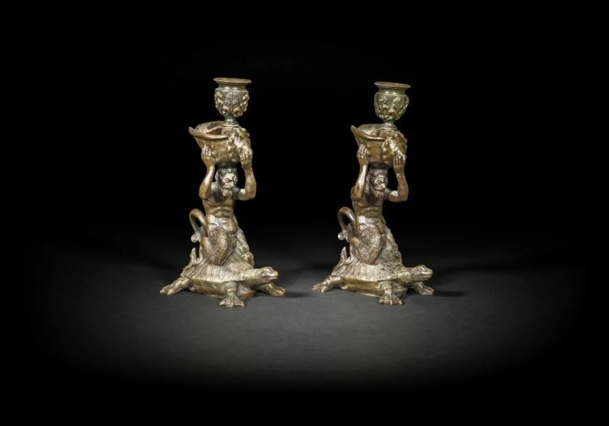 Paire de flambeaux en bronze patiné, à figure de tritons assis sur une tortue ; (à l’origine probablement sur une base).
XIXe siècle (manque)
H. : 19 cm