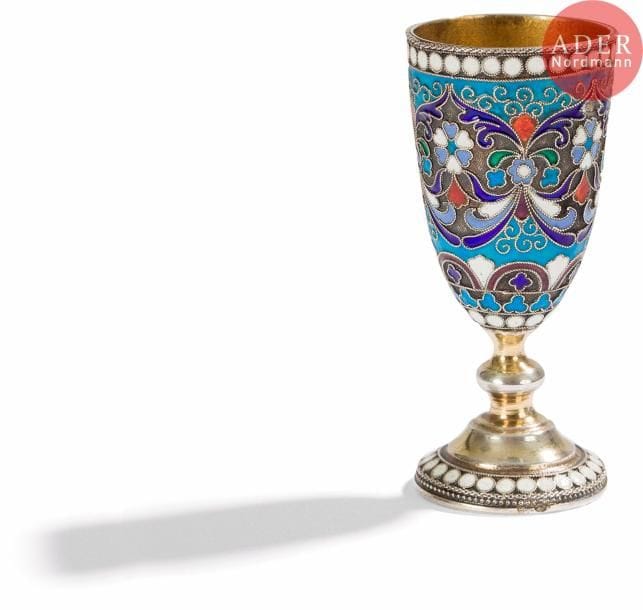 Verre à vodka sur piédouche en vermeil 84 zolotniks (875 millièmes), à décor émaillé polychrome cloisonné de rinceaux feuillagés et fleuris sur fond amati, bordé de perles blanches. Petits chocs.
Probablement Moscou, 1899-1908.
Orfèvre en partie illisible.
H. 7,2 cm. Poids brut : 38,46 g

