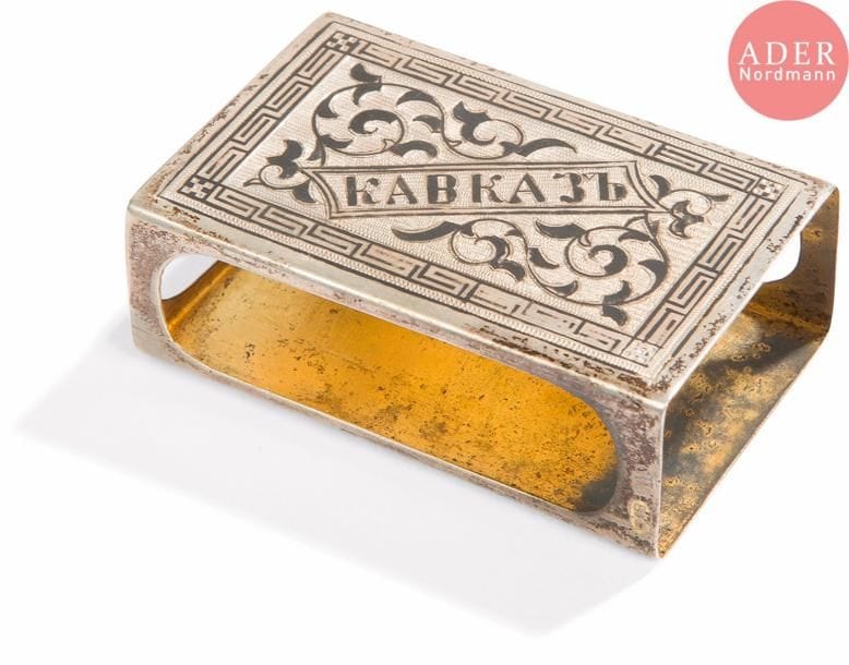 Étui à boîte d’allumettes caucasienne en vermeil 84 zolotniks (875 millièmes), à décor niellé sur les deux faces de rinceaux feuillagés entourant d’un côté l’inscription en russe Caucase. Bon état, légères usures.
Moscou, vers 1890.
Orfèvre : OH ou HO, non identifié.
H. 2 x L. 6,2 x P. 3,8 cm. Poids brut : 29,7 g

