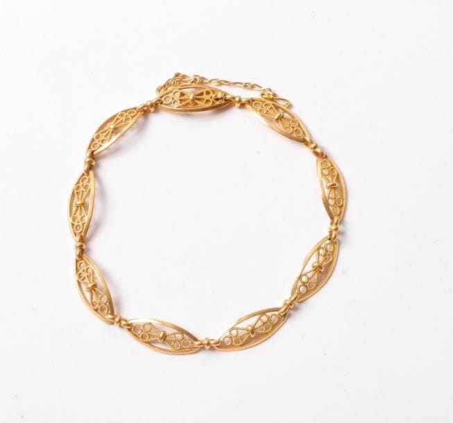 Petit bracelet en or 18K (750) articulé de maillons ovales ajourés et filigranés. Poids: 10 g