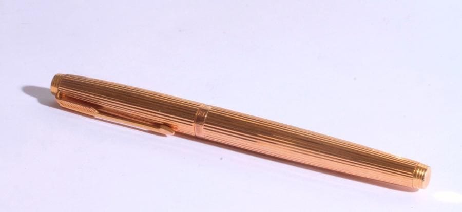 PARKER. Stylo plume en or 18K (750) et corps en métal doré à motif cannelé. Dans un écrin de la Maison Cartier