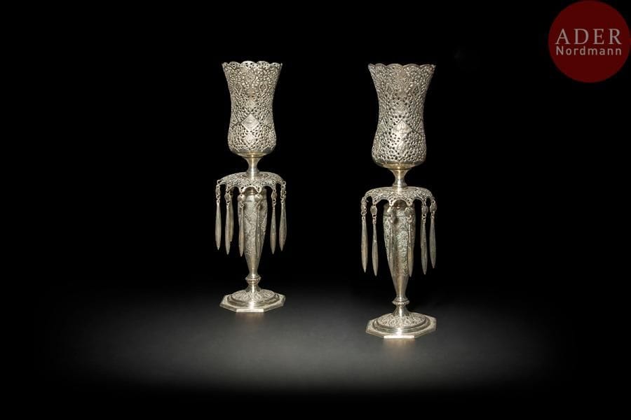 Paire de chandeliers photophores en argent, Iran, Ispahan, XXe siècle
Paire de chandelier en trois parties. Réservoir en forme de tulipe sur fût fusiforme, coupelle à pampilles, reposant sur une base octogonale, à décor découpé et ciselé de médaillons polylobés d’oiseaux affrontés, d’animaux, ou de fleurs. 
Haut. : 44 cm 
P.: 1089 g
État : manquent trois pampilles.
Pair of silver photophores candlesticks, Iran, Ispahan, 20th century.