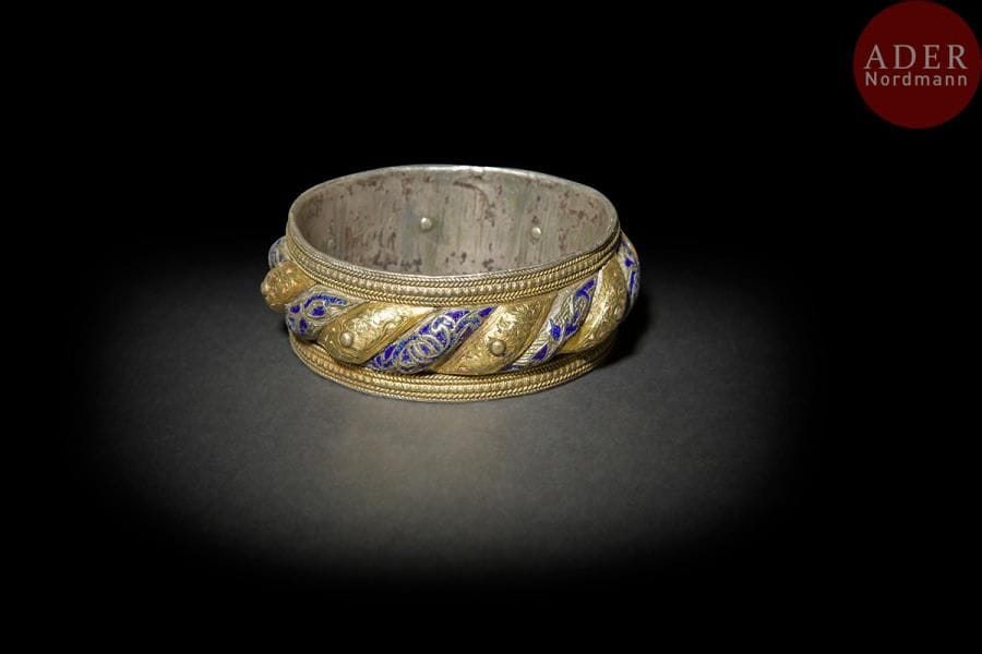 Bracelet shams u-qamar, Nord du Maroc, XIXe siècle
Bracelet à godrons torsadés en argent ciselé de rinceaux émaillés de rouge et bleu, aux côtés alternativement recouverts de feuilles d’or repoussées. 
Diam. : 6,5 cm
PB. : 177 g
A shams u-qmar, silver bracelet, North of Morroco, 19th century.