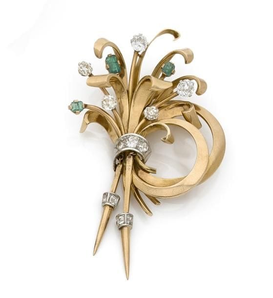 Broche-clip en or 18K (750 ‰), bouquet stylisé, les fleurs en diamants de taille ancienne ou en émeraudes, lien en platine serti de diamants, terminé de deux pampilles mobiles. Travail des années 1940. 
Hauteur : 8,5 cm environ.
Poids brut : 30,9 g