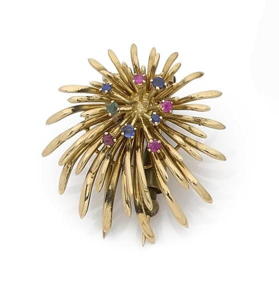 Broche-clip étincelle en or jaune 18K (750 ‰), piqué de rubis, saphirs et une émeraude. Travail français des années 1950. Hauteur : 3,8 cm environ.
Poids brut : 17,5 g (égrisures)