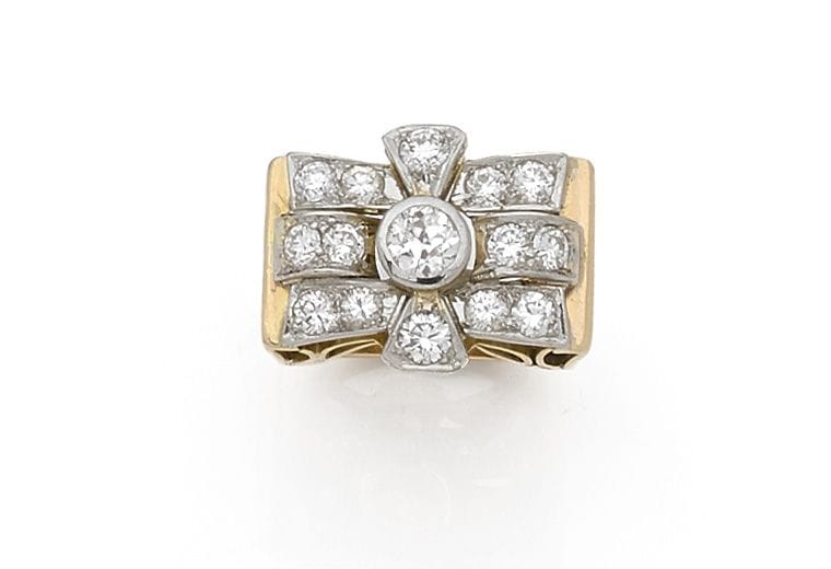 Bague en or 18K (750 ‰) et en platine, ornée d’un diamant dans un nœud de diamants plus petits. Travail des années 1940. Tour de doigt : 49.
Poids brut : 9,6 g