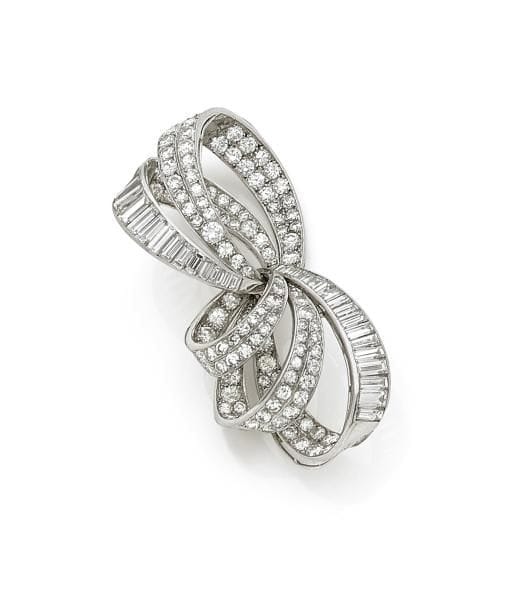CHAUMET.
Broche-clip en platine et en or gris 18K (750 ‰) formé de rubans noués sertis de diamants de taille brillant et calibrés. Signé. 
Hauteur : 5 cm environ.
Poids brut : 19 g