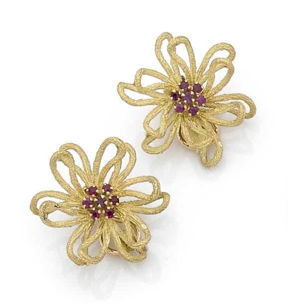 Paire de clips d’oreilles en fils d’or jaune 18K (750 ‰) amati formant des fleurs stylisées, le pistil agrémenté de rubis. 
Hauteur : 2,8 cm environ.
Poids brut : 16,7 g (égrisure)