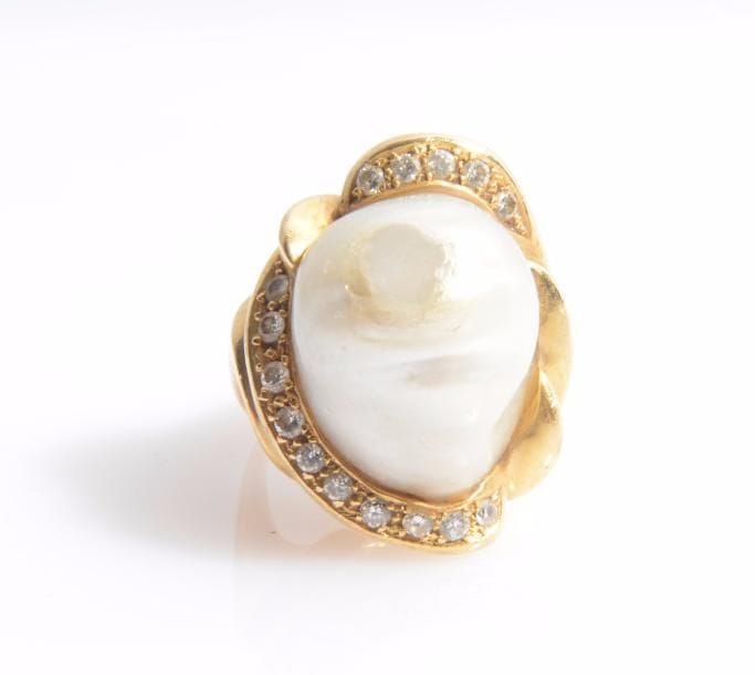 Bague en or 18K (750 ‰), ornée d’une perle de culture fausse, entourée de diamants. 
Tour de doigt : 53.
Poids brut : 24,9 g