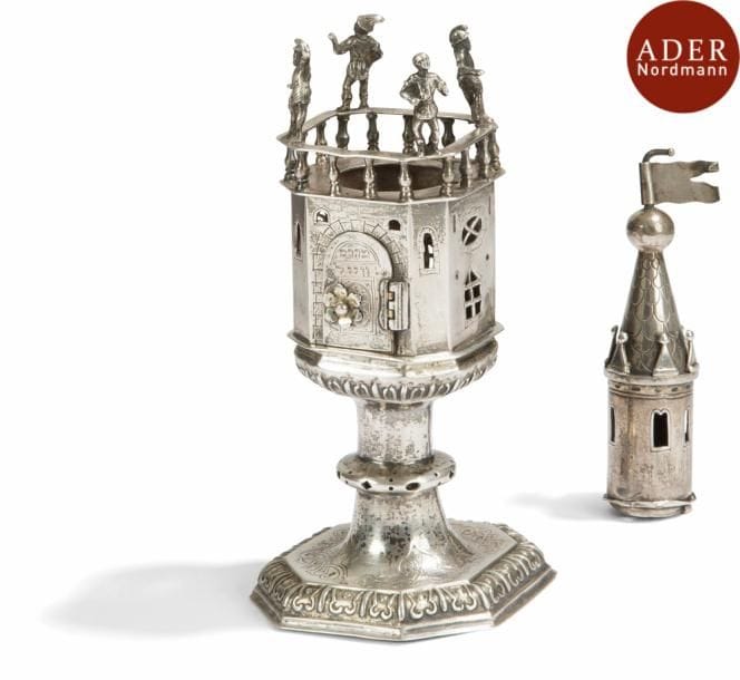[MAHARAM WEILL]
Boîte à aromates
Allemagne, Augsbourg, XVIIe ou XVIIIe siècle
Argent ciselé.
Poinçons d’Augsbourg et poinçons de maître. Boîte en forme de tour octogonale surmontée d’une balustrade ornée d’un personnage sur chacun des angles. La tourelle supérieure est cylindrique puis forme un cône au décor de tuiles et se finit par une sphère et un drapeau. La partie intermédiaire entre le compartiment à aromates et la tourelle supérieur manque.
(Accidents et partie intermédiaire manquante)
Sur la porte, figure le nom  : MAHARAM WEILL et à l’intérieur de la porte le prénom  : Mattel
Ce pourrait être le nom de Rabbi Moché Meir Weil (1599-1658) Rabbin illustre d’une lignée de Rabbin qui possède le Mahari Weill comme ascendant et le Korban Nethanel comme descendant.

Mots clés : judaica, jewish, hebreu, hebrew, rabbin, synagogue, juif, juive, israélite, hebraica, judaism, torah, juden, sionism