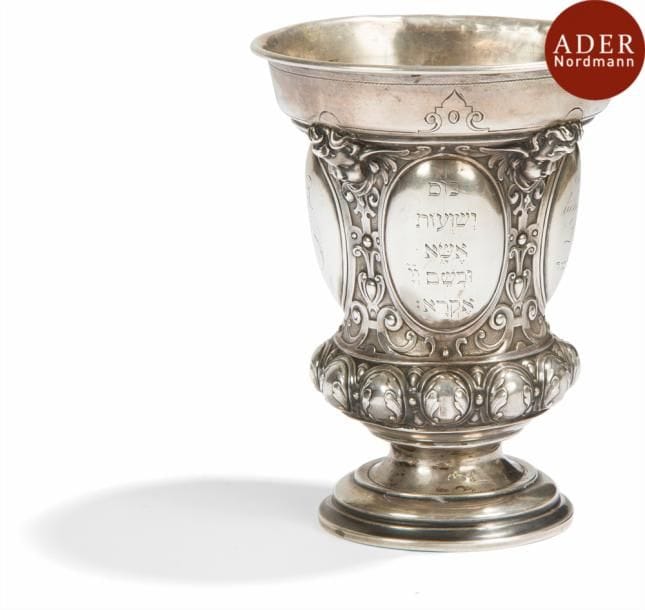 [KOSS]
Coupe de Kiddoush pour la fête de Pessah
Argent fondu et gravé.
Allemagne, XIXe siècle.
Coupe à décor de godrons et têtes de putti. 4 médaillons portent des inscriptions. L’un porte une inscription en allemand et en hébreu indiquant : à notre fils Léopold pour Pessah 1884, le second un monogramme, Le troisième verset des psaumes et le dernier un passage du rituel de Pessah. Petit accident au piédouche.
Hauteur : 12 cm - Poids : 149,8 g.

Mots clés : judaica, jewish, hebreu, hebrew, rabbin, synagogue, juif, juive, israélite, hebraica, judaism, torah, juden, sionism
