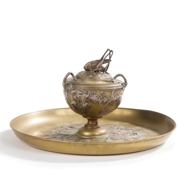Henri HUSSON (1852-1914) 

Sauterelle et lierre
Rare urne couverte à trois anses détachées sur son présentoir.
Épreuve en bronze patiné aux motifs décoratifs en application réalisés en argent.
La prise, zoomorphe et en ronde-bosse, du couvercle de l’urne est également exécutée en argent.
Circa 1908 / 10.
Petites déformations éparses et altérations aux patines, les pattes de l’insecte légèrement tordues, manquent probablement les antennes de l’insecte.
Signée H. HUSSON au revers de la base circulaire et monogrammée H. H. sur l’avers.
Hauteur : 13 cm
Diamètre : 23 cm