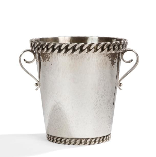 Jean DESPRÉS (1889-1980)

Seau à champagne moderniste en métal argenté.
Le corps à surface martelée reçoit deux prises en volutes, traitées lisses, et accueille une première et large gourmette à maillons plats sur le talon en retrait et une seconde sur le pourtour de la bordure.
Signé et daté J. DESPRÉS 1966 à la pointe sous la base.
Hauteur : 21,5 cm

Provenance :
Ancienne collection M. & Mme L. (L’Isle-sur-Serein – France), œuvre acquise par ces derniers directement auprès de l’artiste.