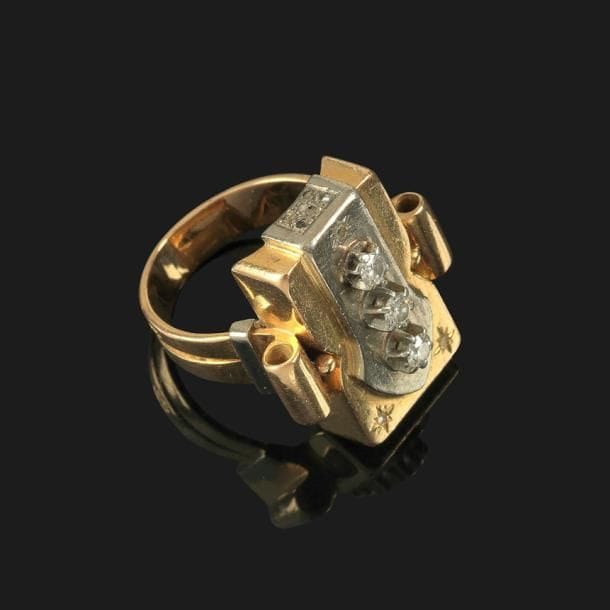 Jean DESPRÉS (1889-1980)

Bague moderniste en or jaune, or blanc et diamants.
La plateforme rectangulaire à étranglement présente un décor central géométrique accueillant une série de trois diamants.
Une des deux parties latérales reçoit un pavement d’éclats de diamant.
L’anneau se termine, sous la plateforme, par un enroulement à chacune de ses extrémités et reçoit des barrettes décoratives.
Signée J. DESPRÉS (en grande partie effacé) à la pointe à l’intérieur de l’anneau et porte les poinçons de Maître Orfèvre et de garantie sur l’anneau.
Poids brut : 13,4 g

Provenance :
Ancienne collection M. & Mme G. (Près Montbard – France), œuvre acquise par ces derniers directement auprès de l’artiste.