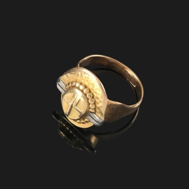 Jean DESPRÉS (1889-1980)

Bague moderniste en or jaune et or blanc.
La plateforme asymétrique présente un décor central monogramme sur un fond en retrait, traité en martelage pour moitié, accueillant des rangées tournantes perlées.
Motifs ornementaux de deux doubles barrettes en or blanc. 
Porte les poinçons de Maître Orfèvre (en partie effacé) et de garantie sur l’anneau.
Poids : 14,9 g

Provenance :
Ancienne collection M. & Mme P. (Avallon – France), œuvre acquise par ces derniers directement auprès de l’artiste.