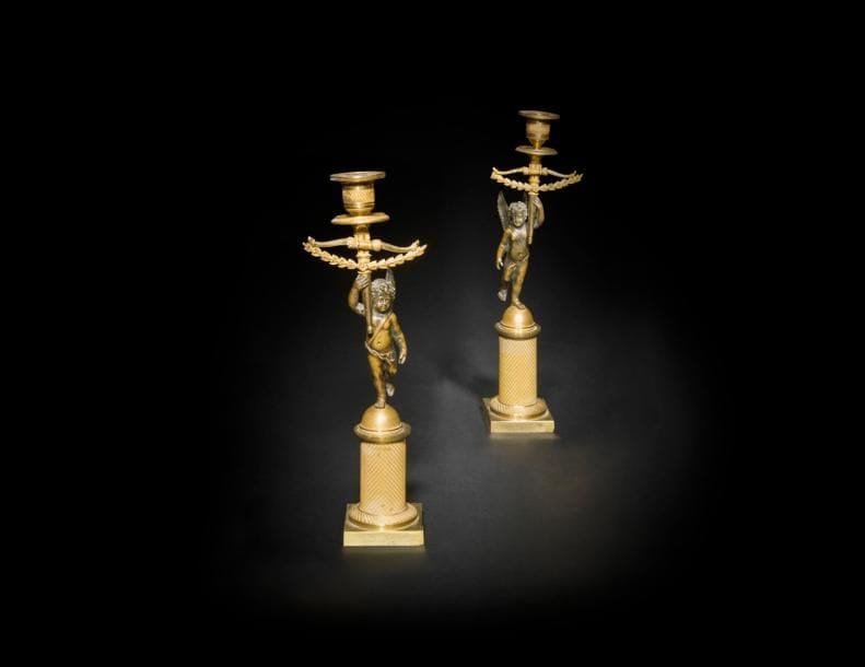 Paire de flambeaux aux enfants ailés en bronze patiné et doré, chaque figure tenant un bras de lumière orné d’un arc.
Époque Restauration (usures).
H : 25 cm