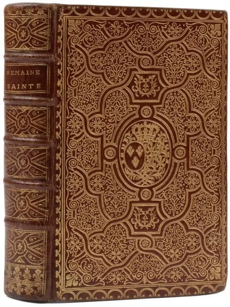 [RELIURE].
L’Office de la semaine sainte en latin et en françois. Selon le missel et le bréviaire romain, & le nouveau Missel & Bréviaire de Paris. Avec des réflexions et méditations, Prieres & Instructions pour la Confession & Communion. Dédié à la reine, pour l’usage de sa Maison.
Paris : Jean-Baptiste Garnier, 1752. — In-8, 198 x 124 : (2 ff.), xlviij, 852 pp. Maroquin rouge, riche plaque dorée à la fanfare et armes dorées au centre sur les plats, dos à nerfs orné, roulette dorée intérieure, doublures et gardes de papier doré et en couleurs à motifs de feuilles et de fleurs, tranches dorées (reliure de l’époque).{CR}Édition illustrée d’un joli bandeau allégorique aux armes de la reine.
Superbe exemplaire en reliure de l’époque aux armes de la reine Marie Leszczynska, décorée d’une belle et riche plaque à la fanfare.
C’est l’une des dernières apparitions anciennes de ce décor qui fut très prisé pendant trois siècles, avant le renouveau apporté par Thouvenin.
Exemplaire parfaitement conservé.