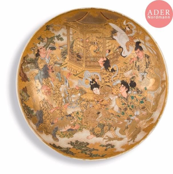 JAPON - Époque MEIJI (1868 - 1912)
Plat rond en faïence de satsuma à décor émaillé polychrome et or des huit immortels devant un temple.
Diam. : 45 cm. 