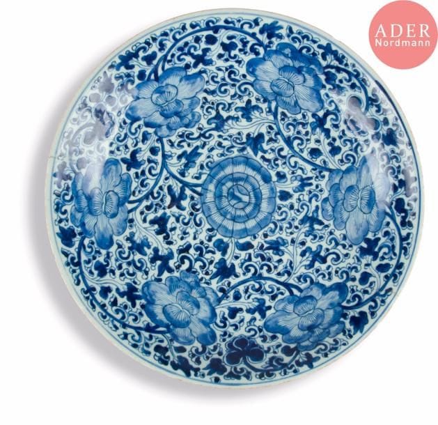CHINE - Époque KANGXI (1662 - 1722)
Plat rond en porcelaine bleu blanc à décor de lotus dans leur feuillage.
Diam. : 39,6 cm. (Restauration, éclats, égrenures).