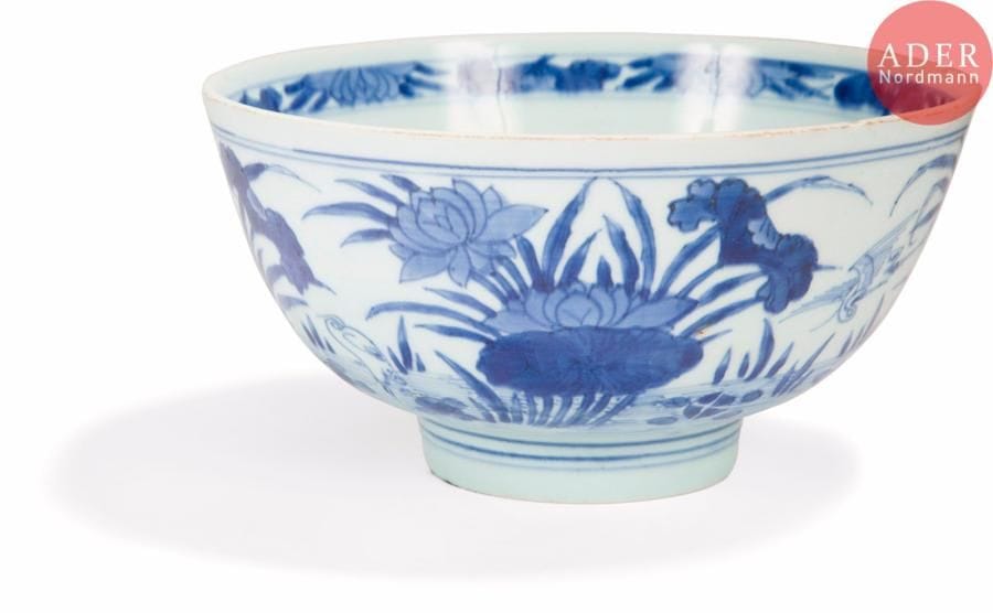 CHINE - Époque KANGXI (1662 - 1722) 
Bol en porcelaine décorée en bleu sous couverte d’aigrettes parmi les fleurs de lotus. Marque apocryphe de Xuande. (Fêlure au talon, égrenure). 
Diam. : 20 cm