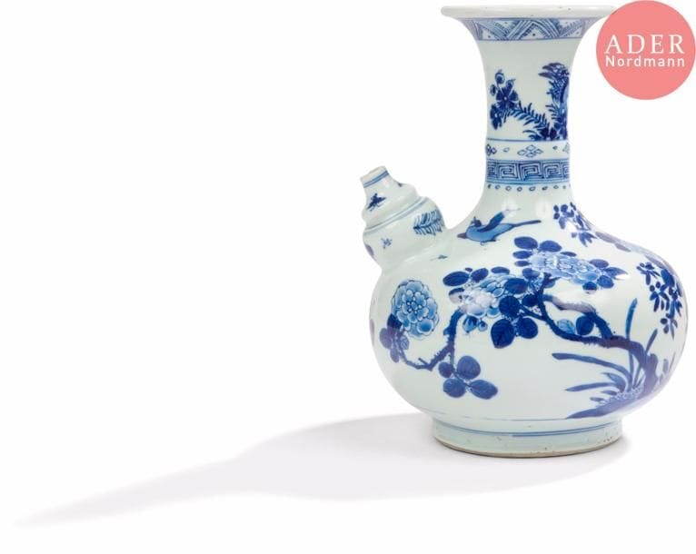 CHINE - XVIIIe siècle
Kendi en porcelaine bleu blanc à décor d’oiseau en vol et d’un oiseau perché sur un rocher parmi des branches fleuries. (Égrenures au bec verseur).
H. : 24,5 cm. 

On y joint un petit vase couvert en porcelaine bleu blanc à décor de panneaux fleuris et de personnages. (Éclats au col et au couvercle, bordure du couvercle recollée, fêlure au col).
H. : 20,2 cm.