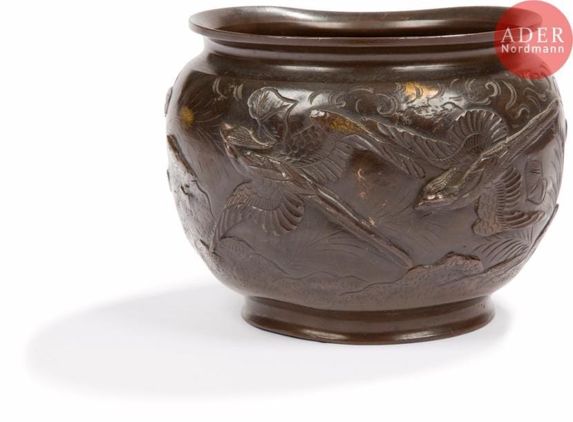 JAPON - Vers 1900
Pot en bronze à patine brune à décor en haut relief de phénix en vol dans un paysage montagneux.
Diam. : 14,6 cm. 