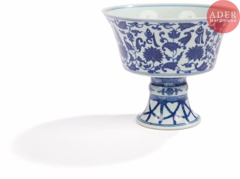CHINE
Coupe à bord évasé sur piédouche en porcelaine à décor bleu sous couverte de fleurs de lotus stylisées et inscriptions en tibétain. Le pied décoré de perles. Au revers, la marque apocryphe de Qianlong en zhuanshu.
H. : 13 cm. Diam. : 15 cm. 