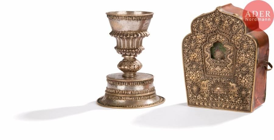 TIBET - XIXe siècle
Autel portatif dit « ga’u » en laiton et argent réticulé et une lampe à beurre sur piédouche en argent.
H. : de 14,6 à 15, 9 cm. PB. :580 g.