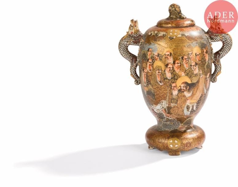 JAPON, Fours de Satsuma
Époque MEIJI (1868 - 1912)
Vase couvert quadripode en faïence de Satsuma émaillée polychrome et or des 18 Luohan, les anses formant dragons, la prise du couvercle formant un luohan assis. Signé Dai Nihon Satsuma koku Fujiyama sei. (Manque la tête, restauration, accidents).
H. : 24 cm.