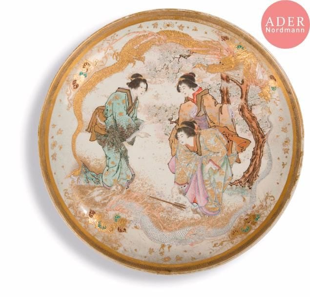 JAPON - Époque MEIJI (1868 - 1912)
Plat rond en faïence de satsuma à décor émaillé polychrome et or de trois jeunes femmes sous un cerisier en fleur une flèche à terre et deux dragons, des araignées dans leur toile le long de la réserve.
Diam. : 30,2 cm. 