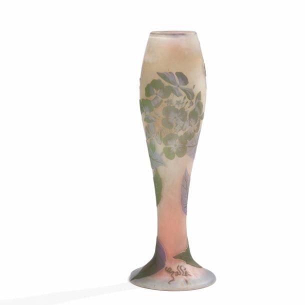 Établissements GALLÉ (1904-1936) 
Hortensias 
Vase fuselé sur large base circulaire. Épreuve en verre multicouche au décor, dégagé à l’acide, traité lavande et vert sur fond gris nuancé. Deux éclats sur le pied. Signé GALLÉ, en réserve gravé en camée à l’acide sur le pied. H. 34 cm