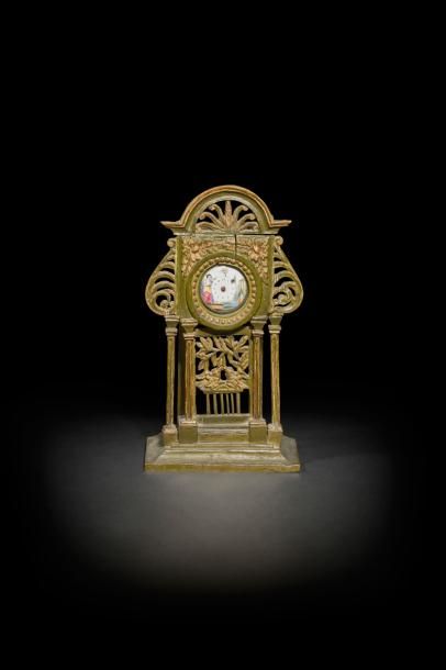 Montre et porte-montre en bois peint de forme portique surmonté d’un fronton à décor de palmette, la montre en émail polychrome à décor d’une felle jouant de la lyre.
Début du XIXe siècle (accidents et manques)
H : 27 cm, L : 15 cm