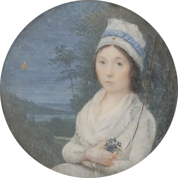 École FRANÇAISE vers 1789-90
Jeune femme coiffée d’une charlotte à nœud bleu, assise dans un paysage nocturne, tenant un bouquet de pensées
Miniature sur ivoire de la fin du XVIIIe siècle, diam. à vue 5,9 cm (fente, accidents)
Cadre à miniature en bois vernis et visière de laiton, XIXe siècle, rect. 12 x 11,6 cm (fente)