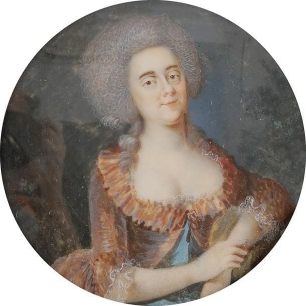 École FRANÇAISE vers 1785
Femme à mi-corps, les deux mains visibles, accoudée de trois-quarts à droite dans un paysage, en caraco saumon à reflets changeants et frange gaufrée, noué sur sa robe bleu turquoise, vers 1785
Miniature sur ivoire du XVIIIe siècle, diam. 6,9 cm (fente en haut à droite n’affectant pas le sujet).
Cadre à miniature en bois vernis et visière de laiton, XIXe siècle, rect. 13,5 x 13,6 cm