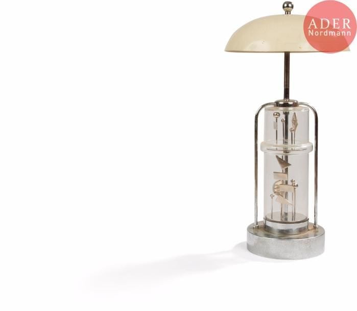 TRAVAIL CINÉTIQUELampe à poser, base en métal chromé, fût cylindrique en verre renfermant des éléments géométriques mobiles entrainés par un moteur rotatif. Abat-jour champignon en métal laqué crème surmonté d'une boule chromée. Métal oxydé, usures et frottements à l'abat-jour, salissures. H. 53 cm