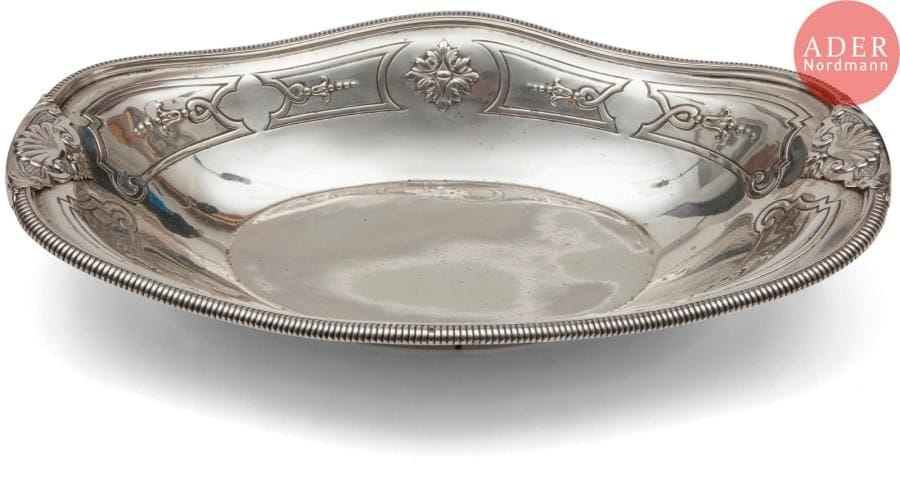 Bassin d’aiguière en argent reposant sur une légère bâte, mouluré de godrons et ciselé au repoussé de coquilles et de rinceaux dans quatre cartouches.
Poinçon minerve
Orfèvre : illisible
Poids : 881,20 g - longueur : 36 cm - largeur : 23,5 cm
